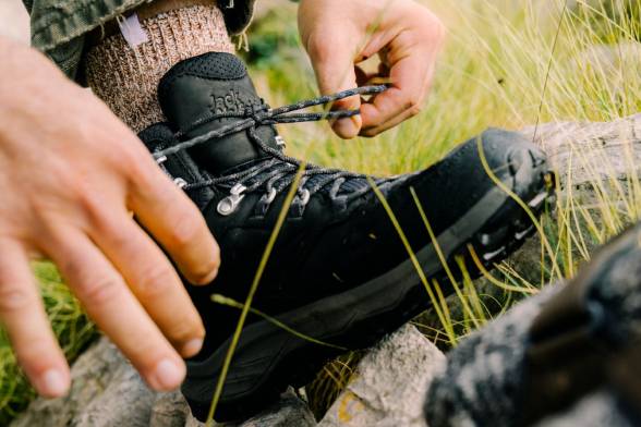 Primer plano de un hombre con botas de montaña negras atándose los zapatos