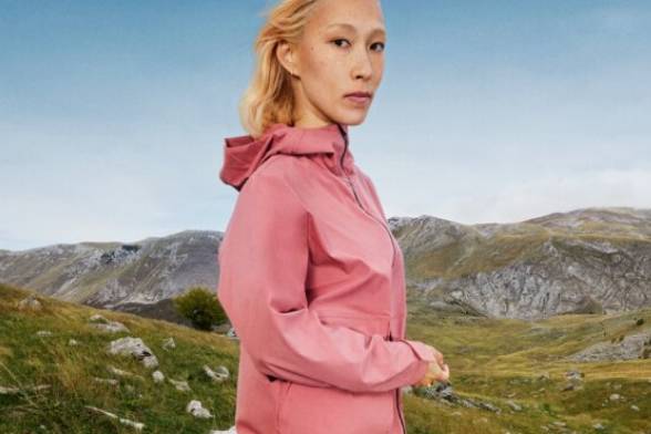 Mujer joven con ropa deportiva de senderismo en un paisaje veraniego de montaña