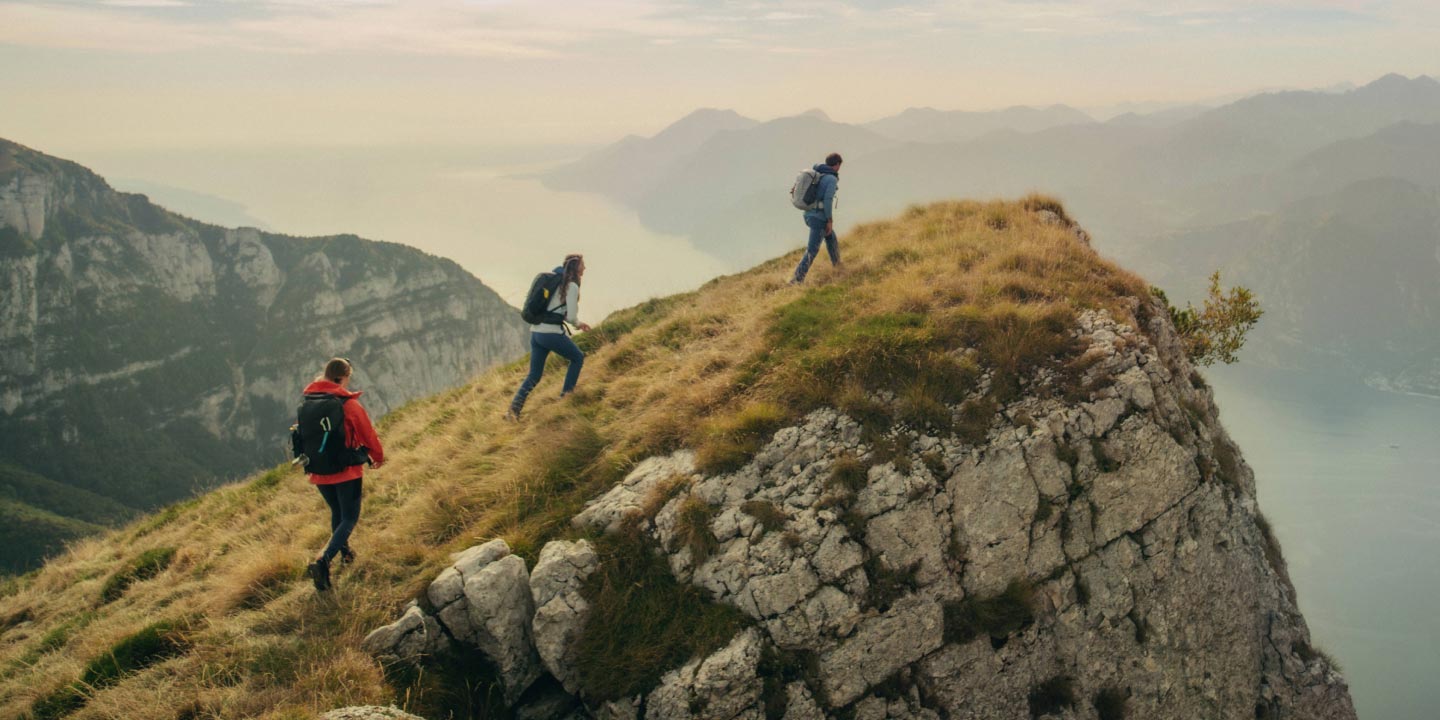 Tres senderistas ascienden una roca en un entorno montañoso