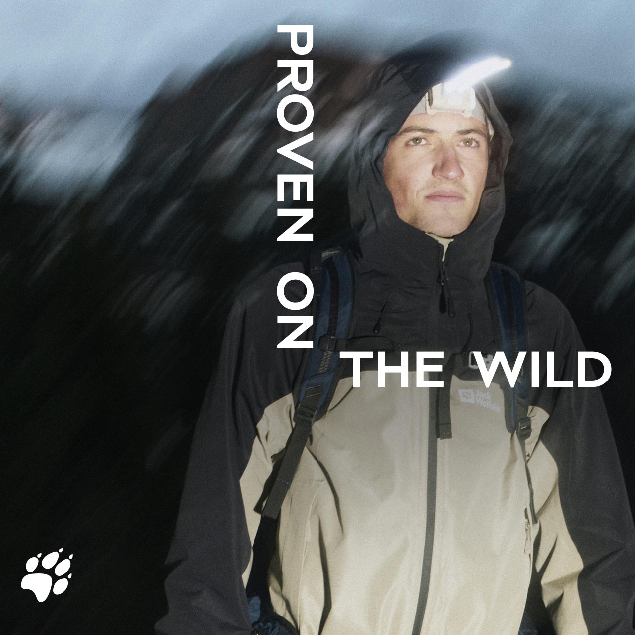 Una persona en una chaqueta con capucha durante una noche en el exterior con una linterna frontal. El texto dice «Proven on the wild»