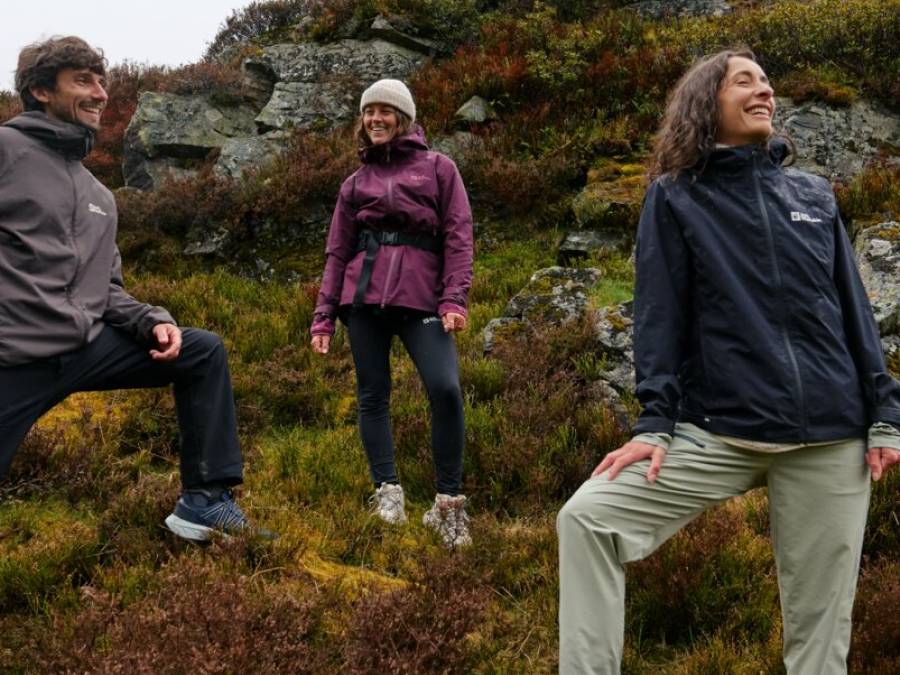 Tres amigos sonrientes en un entorno rocoso con la vista perdida en el paisaje