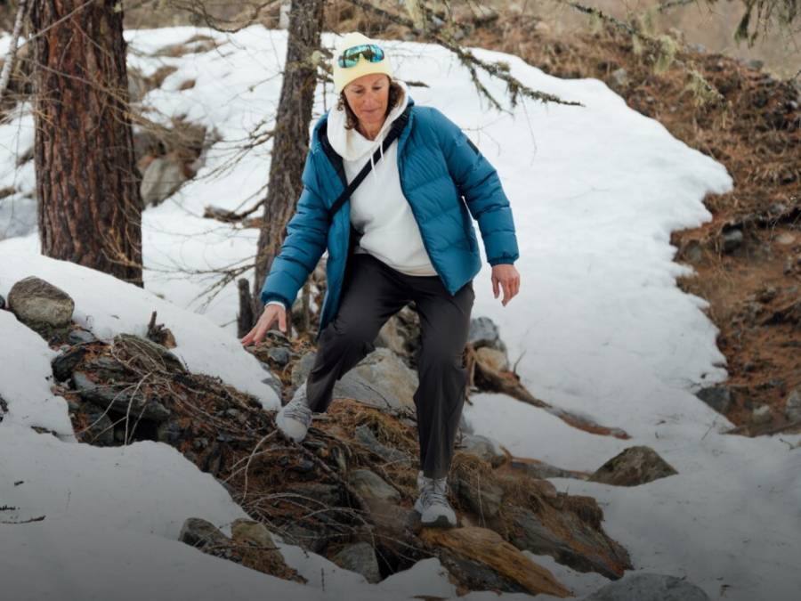 Dos trineos con dos personas cada uno bajan por una pista nevada. Las personas ríen y llevan ropa de invierno, gorros y gafas de sol; al fondo se ven montañas cubiertas de nieve.