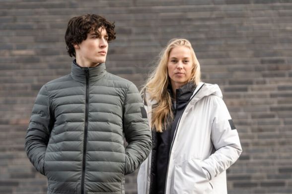 Una mujer y un hombre con chaquetas de invierno informales delante de una pared