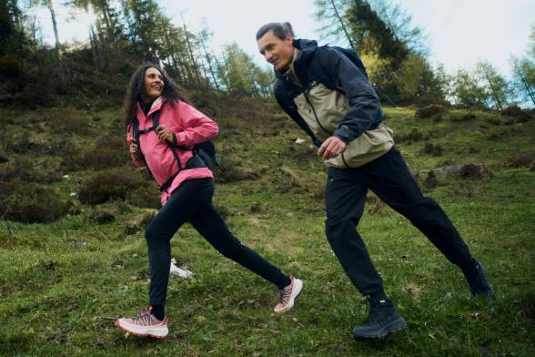 Una mujer y un hombre en ropa de senderismo deportiva cruzan un claro