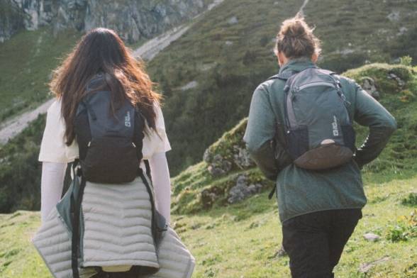 Toma veraniega de dos excursionistas con mochilas de senderismo en look deportivo de espaldas