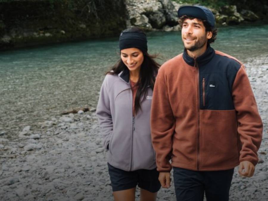 Dos jóvenes adultos con chaquetas de forro polar deportivas frente a un lago