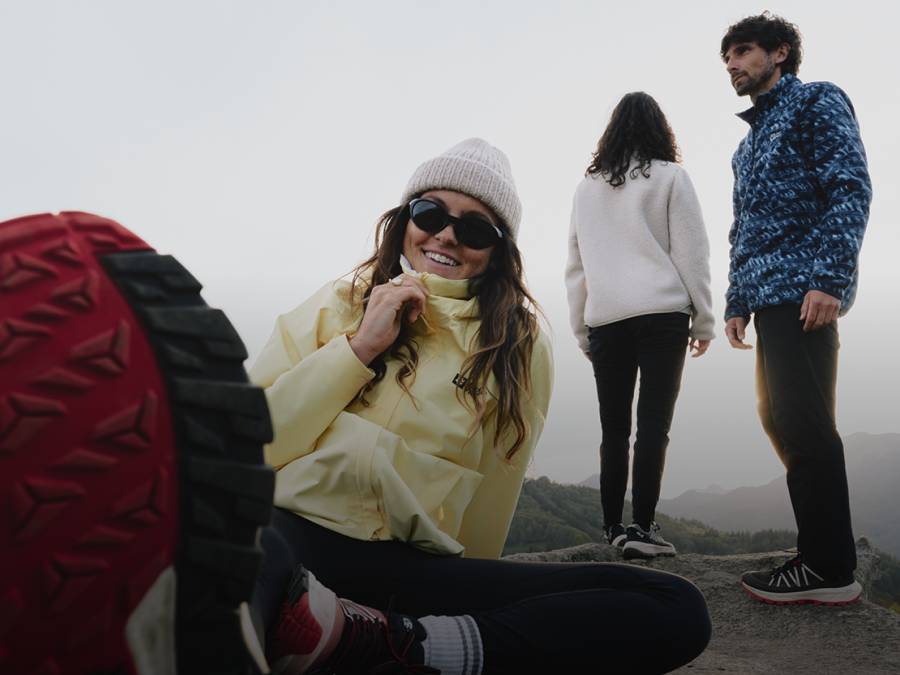 Tres jóvenes adultos con ropa outdoor deportiva en un paisaje montañoso
