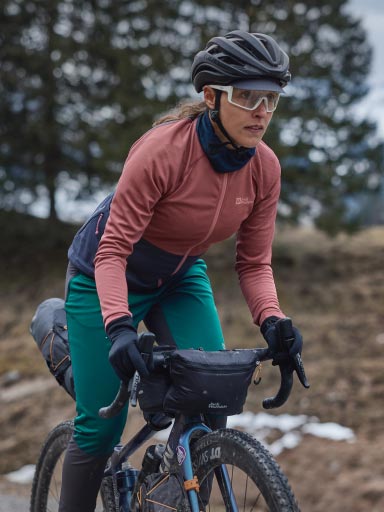 Un hombre vestido con un maillot de ciclista saca su bebida de una riñonera