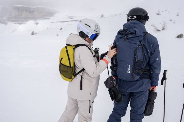 Mujer y hombre con ropa de esquí en un paisaje montañoso nevado