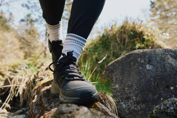 Primer plano de una persona con botas de montaña corriendo sobre una roca