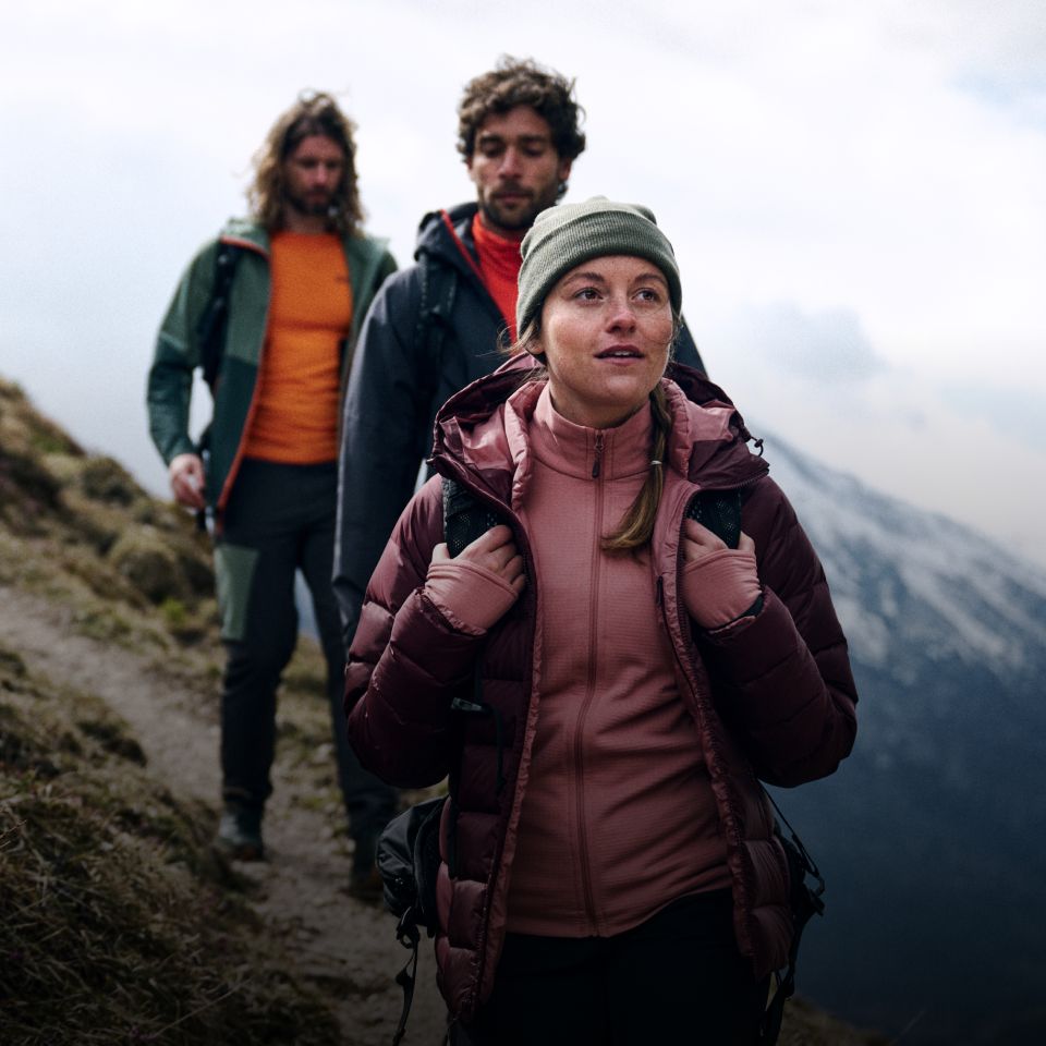 Tres excursionistas con ropa de abrigo caminando por una montaña