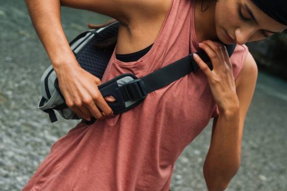 Mujer joven con ropa deportiva y veraniega de senderismo con una bandolera deportiva