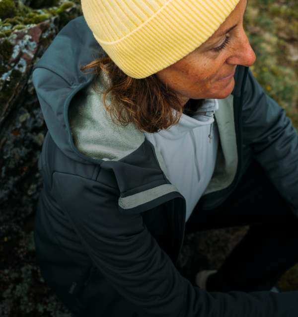 Una señora con forro polar y chaqueta descansado sobre una roca.